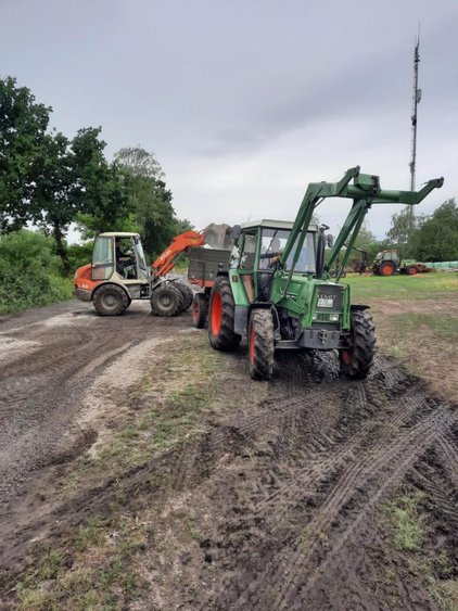 ein Radlader und ein Frontladertraktor stehen auf einem unbefestigten Weg