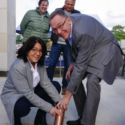 Zwei Personen setzen eine Kupferkapsel in ein Loch; andere beobachten.