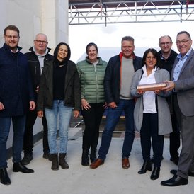 Grundsteinlegung Kindertagesstätte Südwinsen eine Gruppe von Menschen, die in einem Rohbau stehen. Eine Person hält eine Zeitkapsel