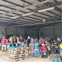Lindhorst Gruppe Menschen füllen Sandsäcke in einer großen Lagerhalle.