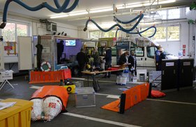 Hochwasseraktionstag Ein Raum mit verschiedenen technischen Geräten und Ausrüstungen, Menschen arbeiten daran.