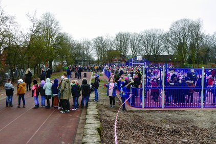 Menschenmenge auf einem Sportplatz, teilweise hinter einer Spielfeldbegrenzung.