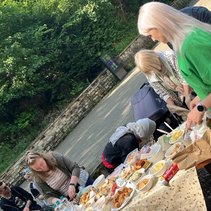 Menschen bedienen sich an einem Tisch voller Essen im Freien.