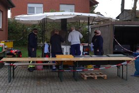 Hochwasseraktionstag Vier Personen in Uniformen bereiten Essen an einem Grillstand im Freien zu.