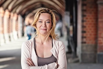 Katja Heinrich steht mit verschrenkten Armen vor einem Gebäude