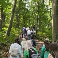 Bericht zur Bildungsreise mit Migranten zum Denkmal Kaiser Wilhelm Gruppe von Menschen wandert auf einem Waldweg bergauf.