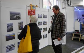 Zwei Personen betrachten eine Fotoausstellung mit Bildern und Infos auf Stellwänden.