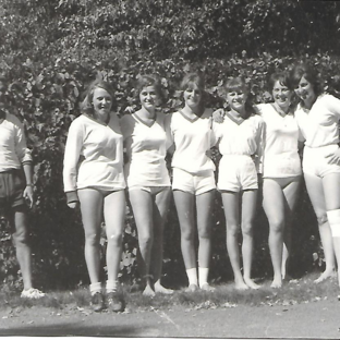 Faustballmannschaft mit Trainer, 1960er-Jahre. Schwarz-weiß-Foto von sechs Faustballspielerinnen in Sportkleidung mit ihrem Trainer, aufgenommen im Freien in den 1960er-Jahren.