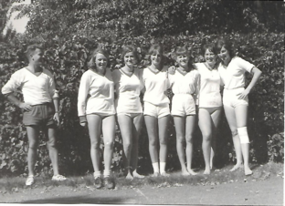 Faustballmannschaft mit Trainer, 1960er-Jahre. Schwarz-weiß-Foto von sechs Faustballspielerinnen in Sportkleidung mit ihrem Trainer, aufgenommen im Freien in den 1960er-Jahren.