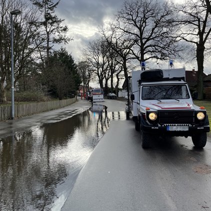 Winser DLRG-Ortsgruppe im Einsatz gegen das Hochwasser Einsatzfahrzeug vor überschwemmter Straße mit reflektierendem Wasser.