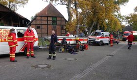 Hochwasseraktionstag Rettungskräfte stehen neben Einsatzfahrzeugen und Ausrüstung auf einer Straße.