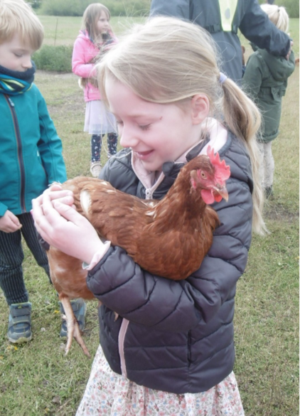 ein kleines Mädchen, das ein Huhn in ihren Händen hält
