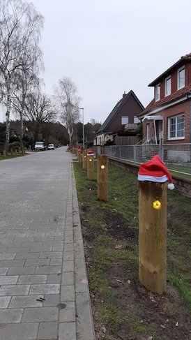 Bild von einer Straße, gesäumt mit Holzpollern, die Nikolausmützen tragen