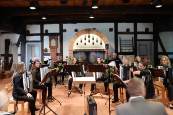 Eine Gruppe von Akkordeonspielern sitzt in einem Raum und bereitet sich auf ein Konzert vor.