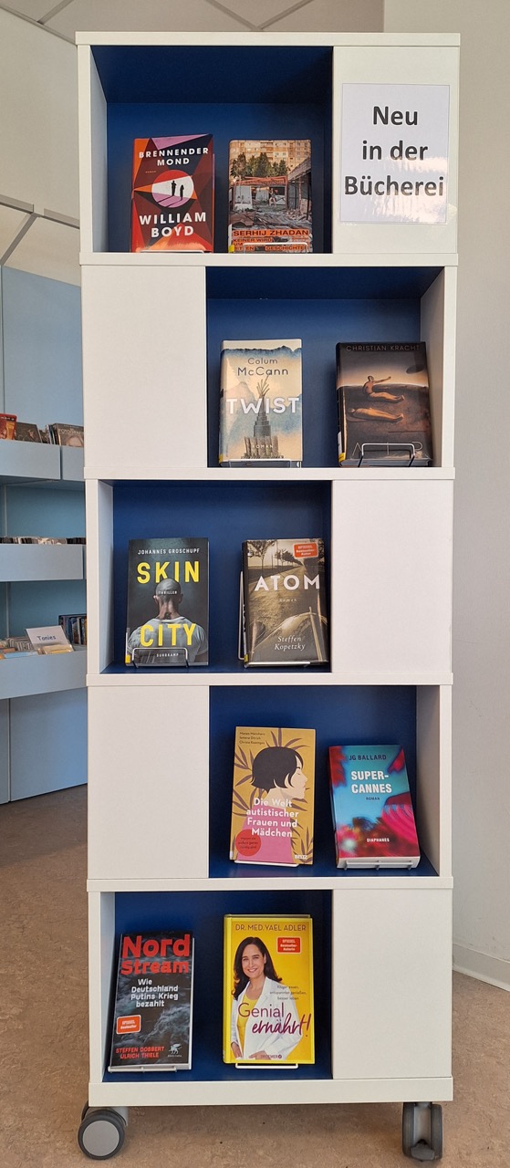 ollregal mit 10 aktuellen Büchern in der Bücherei, Schild: „Neu in der Bücherei“.